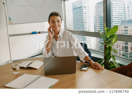 A professional woman confidently working in a modern office environment and setting 117696748