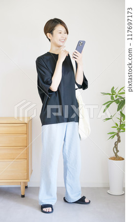 The whole body of a woman operating a smartphone The whole body of a woman operating a smartphone 117697173