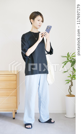 The whole body of a woman operating a smartphone 117697179