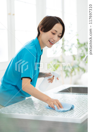 A woman from a housekeeping service cleaning the kitchen 117697310