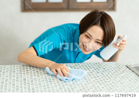A woman from a housekeeping service cleaning the kitchen A woman from a housekeeping service cleaning the kitchen 117697419