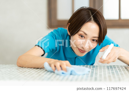 A woman from a housekeeping service cleaning the kitchen A woman from a housekeeping service cleaning the kitchen 117697424