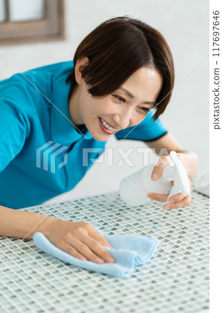 A woman from a housekeeping service cleaning the kitchen A woman from a housekeeping service cleaning the kitchen 117697646