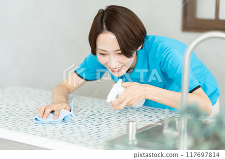 A woman from a housekeeping service cleaning the kitchen A woman from a housekeeping service cleaning the kitchen 117697814