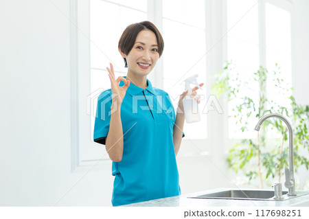 A woman from a housekeeping service cleaning the kitchen 117698251