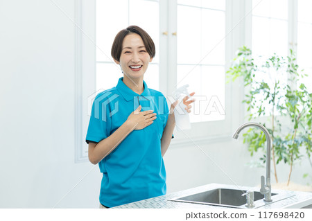 A woman from a housekeeping service cleaning the kitchen 117698420