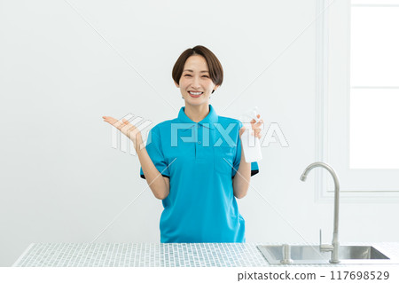 A woman from a housekeeping service cleaning the kitchen 117698529