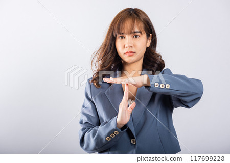 Closeup portrait young business woman wearing a suit smiling making time out gesture with hands studio shot isolated on white background, demonstrates break hand sign, stop time with copy space Closeup portrait young business woman wearing a suit smiling making time out gesture with hands studio shot isolated on white background, demonstrates break hand sign, stop time with copy space 117699228