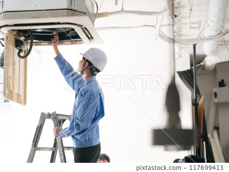 A worker inspecting an air conditioning system 117699413