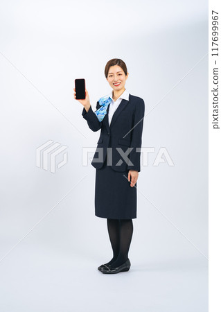 Full-body photo of a middle-aged woman in a suit showing the screen of her smartphone 117699967