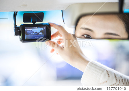 A woman adjusting the position of a drive recorder 117701040