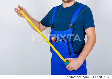 Worker in uniform with a tape measure in his hands 117701487