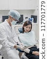 Asian male dentist sharing oral care tips to a patient 117701779