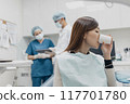 Asian female patient rinsing mouth in between oral care procedure 117701780