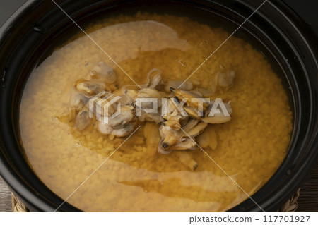 Clam rice. Clam rice cooked in a clay pot. Put clam seasoning into the clay pot. 117701927