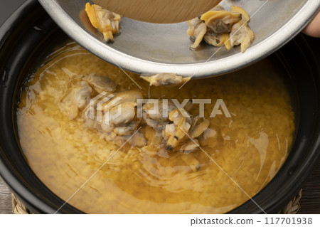 Clam rice. Clam rice cooked in a clay pot. Put clam seasoning into the clay pot. 117701938