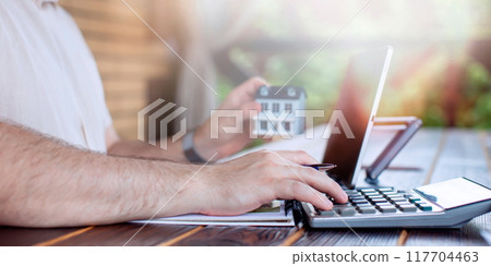 Budget and financial planning concept. Businessman analyzing investment charts with calculator and laptop. Double exposure. 117704463