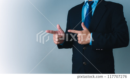 Businessman standing with finger pointing sideways to indicate selection or display of product in advertisement, product and service advertisement, marketing strategy. 117707276