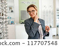 Businesswoman chooses a spectacle frame in an optician's shop 117707548