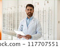 ophthalmologist with eyeglasses using digital tablet while working in optics store 117707551