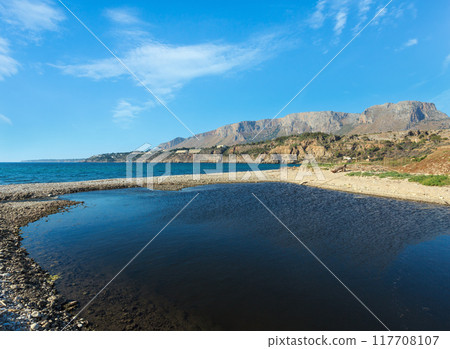 Small river flows into the sea on pebble beach Small river flows into the sea on pebble beach 117708107
