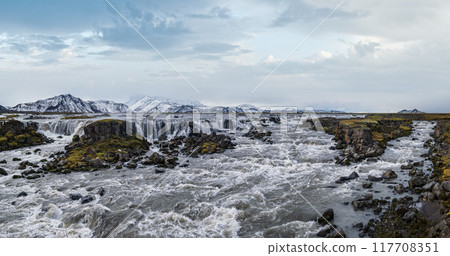 Picturesque waterfal Tungnaarfellsfoss, Iceland, panoramic autumn view Landmannalaugar mountains under snow cover in far. Picturesque waterfal Tungnaarfellsfoss, Iceland, panoramic autumn view Landmannalaugar mountains under snow cover in far. 117708351