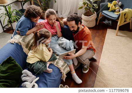 Family Enjoying Tablet Time Together on Cozy Couch 117709076