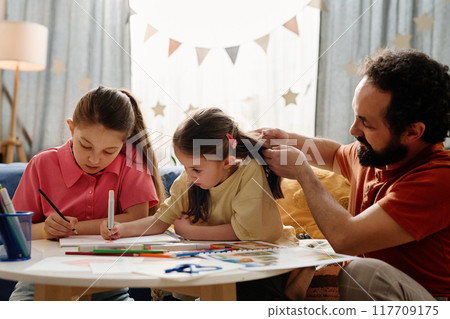 Father Helping Daughters with Homework at Home 117709175