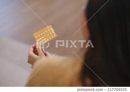 A woman is holding a pill in her hand A woman is holding a pill in her hand 117709335