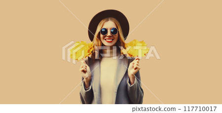 Autumn color style outfit, portrait of beautiful smiling young woman with yellow maple leaves Autumn color style outfit, portrait of beautiful smiling young woman with yellow maple leaves 117710017