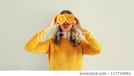 Summer portrait of happy cheerful woman covering eyes with slices of orange looking for something Summer portrait of happy cheerful woman covering eyes with slices of orange looking for something 117710062