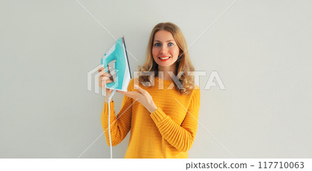 Household chores, ironing - happy smiling woman housewife holding an iron in her hands at home Household chores, ironing - happy smiling woman housewife holding an iron in her hands at home 117710063