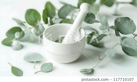 Homeopathic medicine with medicinal plants and crushed leaves in a mortar on a  white background, emphasizing natural healing methods 117710107