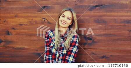 Portrait of beautiful caucasian blonde smiling young woman in casual checkered shirt in the city 117710136