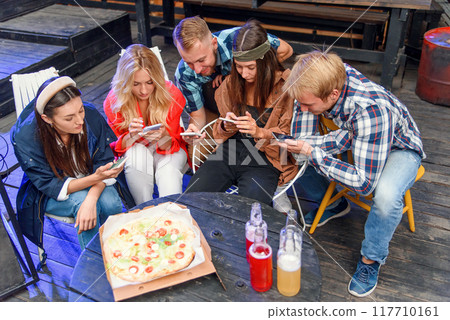 Friends looking at their smartphones at a boring party. Concepts of technology and modern lifestyle problems. Friends looking at their smartphones at a boring party. Concepts of technology and modern lifestyle problems. 117710161