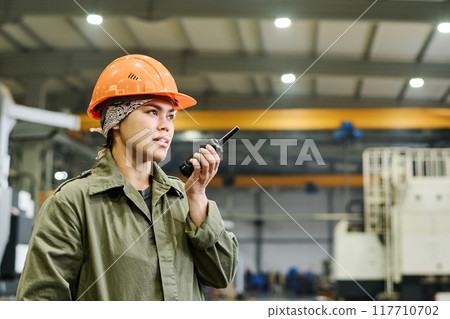 Wearing Hard Hat and Holding Walkie-Talkie in Factory 117710702