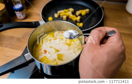 Chef at the kitchen preparing pumpkin porridge with tofu and vegetables Chef at the kitchen preparing pumpkin porridge with tofu and vegetables 117711411