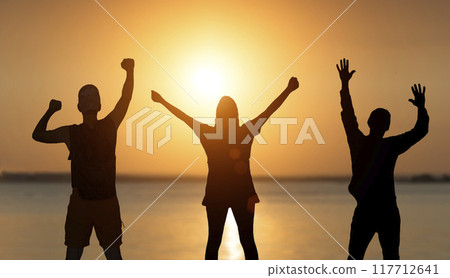 Happy people at sunset enjoy the sun. Teamwork, business, joy of life concept. 117712641