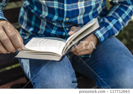 Reading a book. A young man reads a book or a textbook. Education, leisure, business concept. Reading a book. A young man reads a book or a textbook. Education, leisure, business concept. 117712663