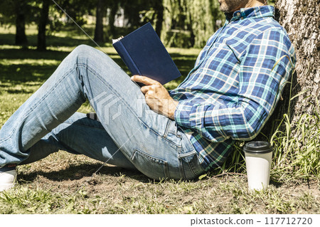 Reading a book. A young man reads a book or a textbook. Education, leisure, business concept. 117712720