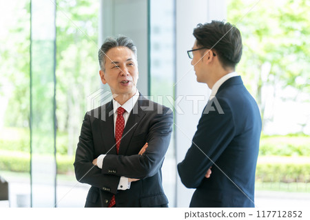 A boss and a subordinate having a conversation in the office lobby A boss and a subordinate having a conversation in the office lobby 117712852