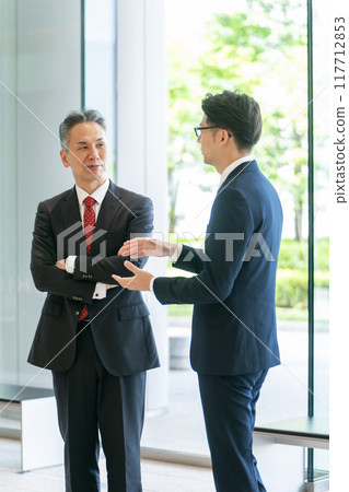 A boss and a subordinate having a conversation in the office lobby A boss and a subordinate having a conversation in the office lobby 117712853