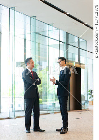 A boss and a subordinate having a conversation in the office lobby A boss and a subordinate having a conversation in the office lobby 117712879