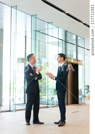 A boss and a subordinate having a conversation in the office lobby A boss and a subordinate having a conversation in the office lobby 117712881