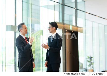 老闆和下屬在辦公室大廳交談 117712883