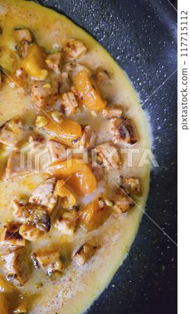 Fried eggs with mushrooms and yellow tomatoes in a frying pan. Home cooking. 117715112