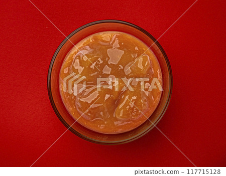 Peach jam in glass bowl isolated on red background with copy space, top view Peach jam in glass bowl isolated on red background with copy space, top view 117715128