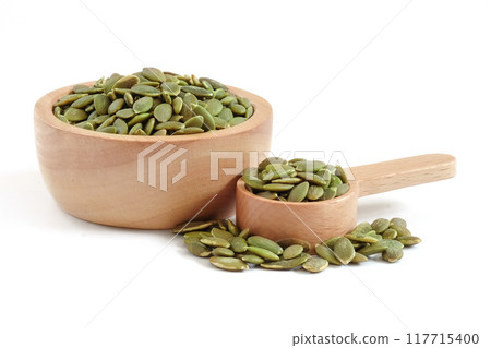 Pumpkin seed in wooden bowl and spoon close up on white background. 117715400