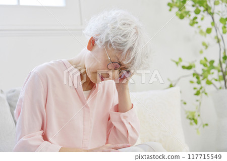 Senior woman with headache in living room Senior woman with headache in living room 117715549