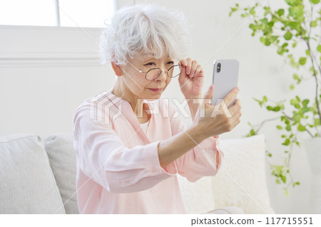 Senior woman with presbyopia looking at a smartphone Senior woman with presbyopia looking at a smartphone 117715551